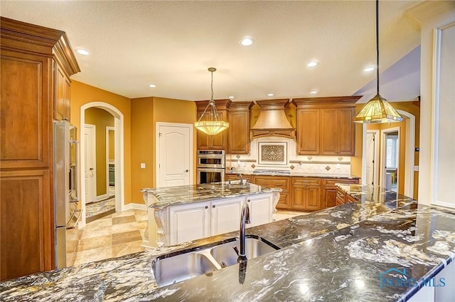 kitchen with dark stone counters, a center island, hanging light fixtures, and appliances with stainless steel finishes