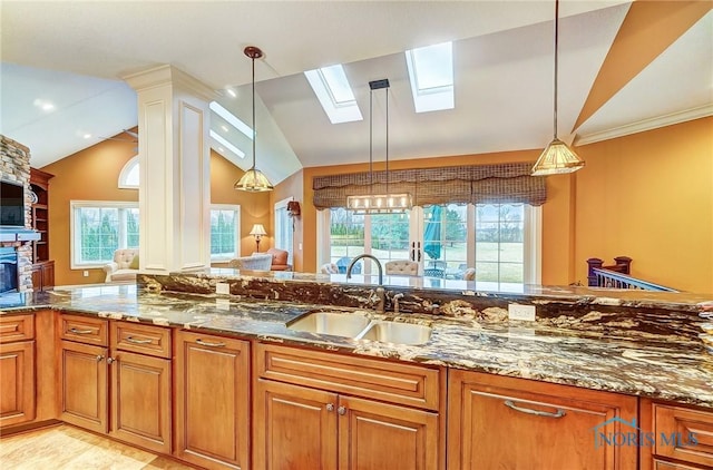 kitchen featuring a fireplace, pendant lighting, lofted ceiling with skylight, and sink