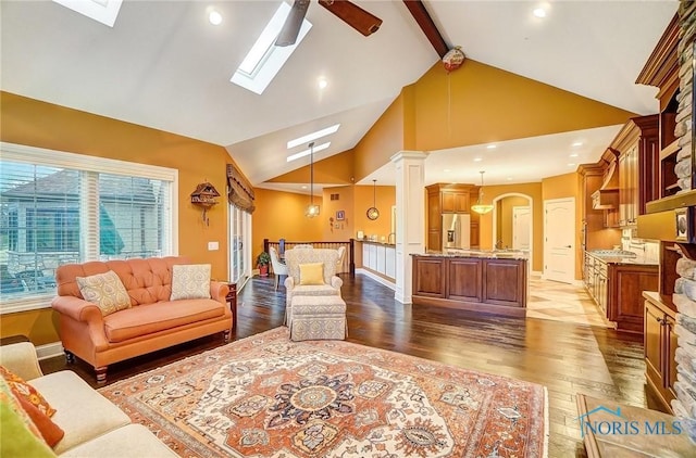 living room with lofted ceiling with skylight, ceiling fan, and dark wood-type flooring