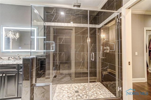 bathroom featuring vanity, an inviting chandelier, ornamental molding, an enclosed shower, and wood-type flooring