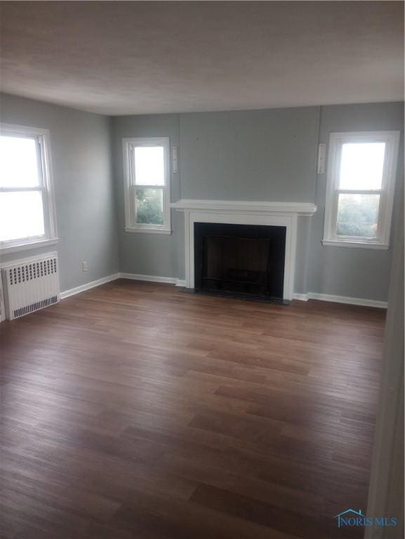 unfurnished living room with radiator heating unit and dark wood-type flooring