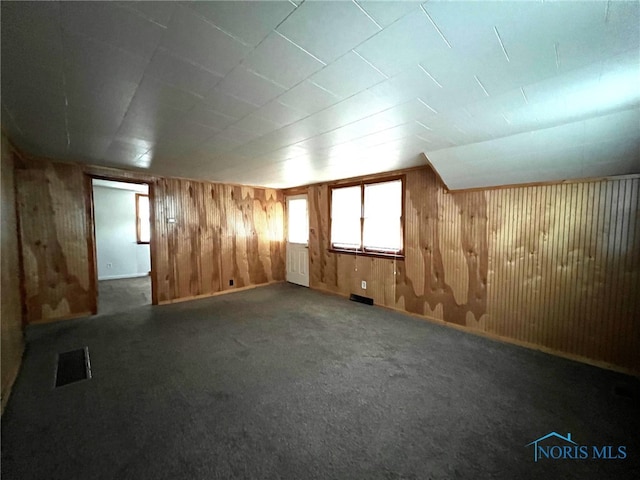 bonus room featuring carpet flooring and wooden walls