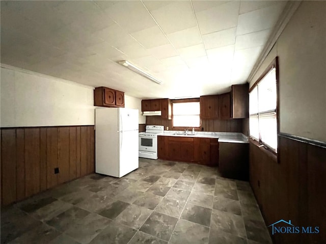 kitchen with wood walls, white appliances, and sink