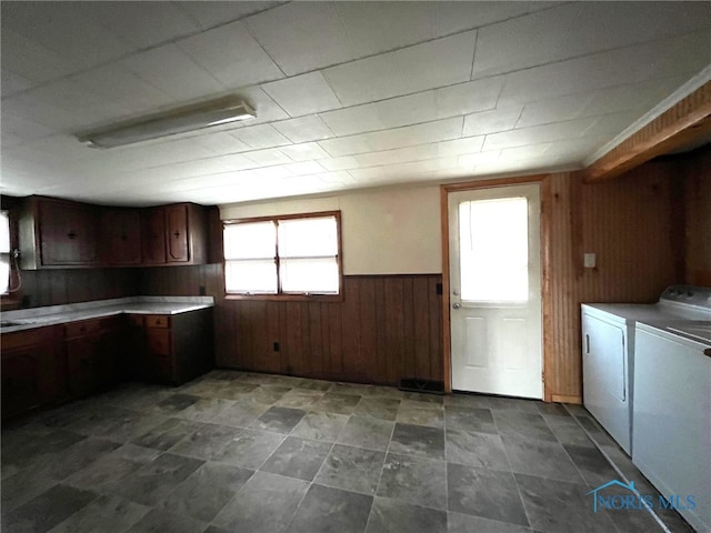 laundry room featuring washer and dryer, cabinets, and wooden walls