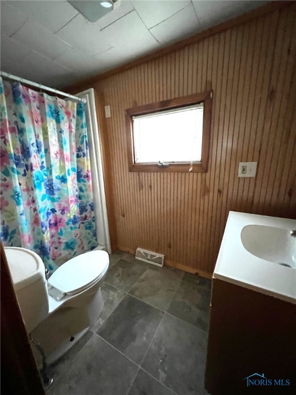 bathroom with a shower with shower curtain, vanity, toilet, and wooden walls