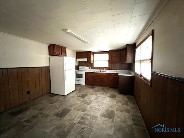 kitchen with wooden walls, sink, and white appliances