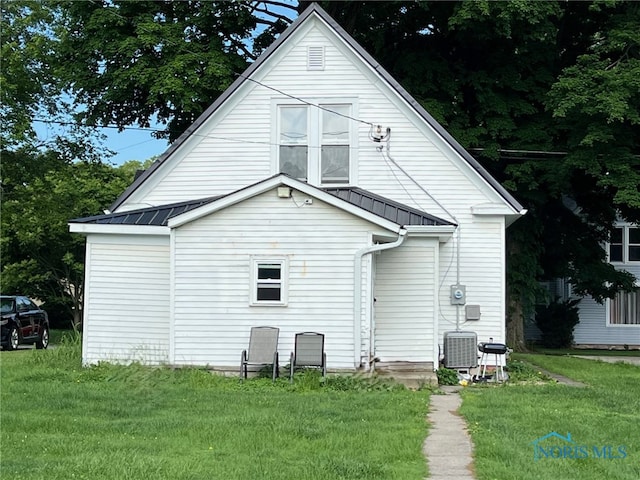 rear view of property featuring a yard and central AC