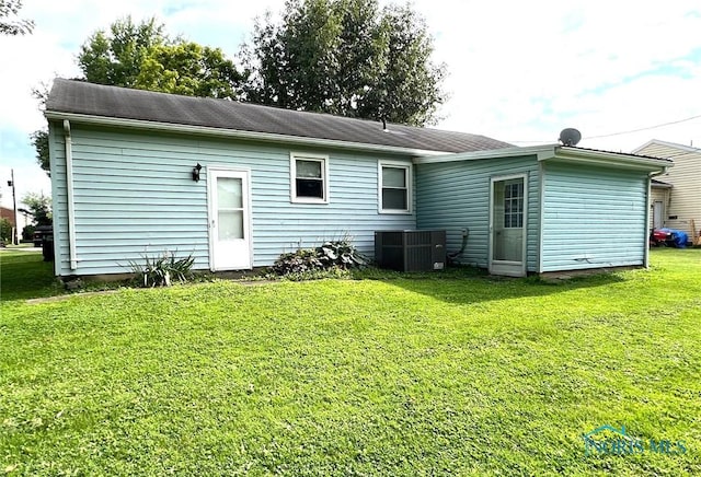 back of property featuring a yard and central AC