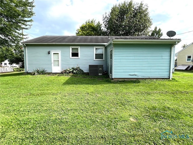 back of property featuring central AC unit and a lawn