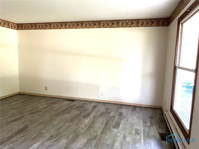 empty room with dark hardwood / wood-style floors and baseboard heating