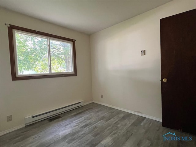 spare room featuring wood-type flooring and a baseboard heating unit