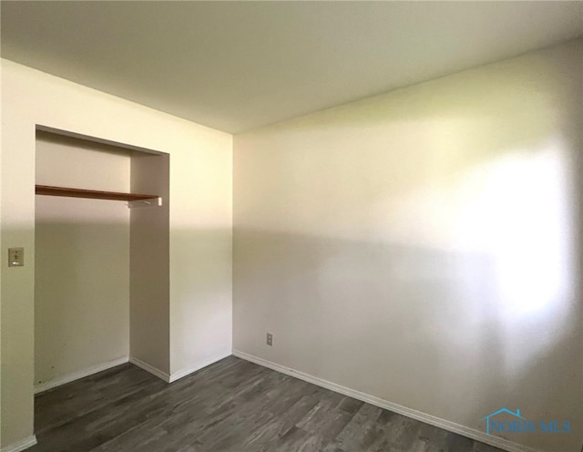 unfurnished bedroom with dark hardwood / wood-style flooring and a closet