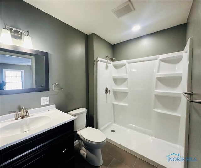 bathroom featuring a shower, tile patterned floors, vanity, and toilet