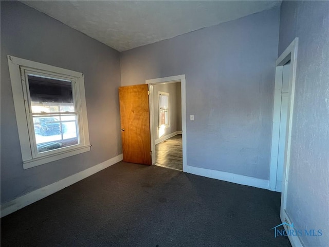 unfurnished room featuring dark colored carpet