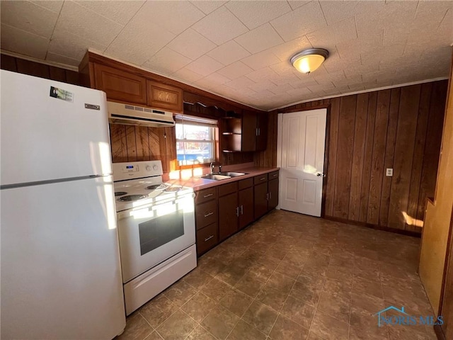 kitchen featuring white appliances, sink, and wooden walls