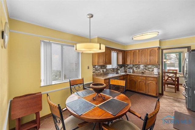 kitchen featuring pendant lighting, decorative backsplash, stainless steel fridge, light tile patterned floors, and dishwashing machine