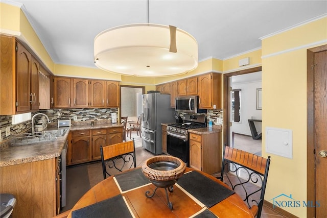 kitchen with backsplash, sink, crown molding, decorative light fixtures, and stainless steel appliances