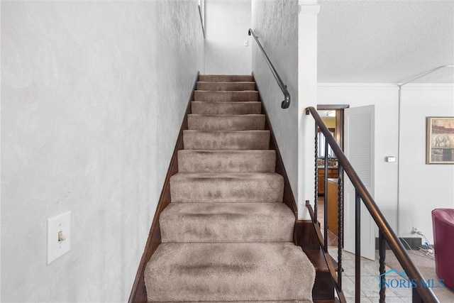 stairway with crown molding and a textured ceiling