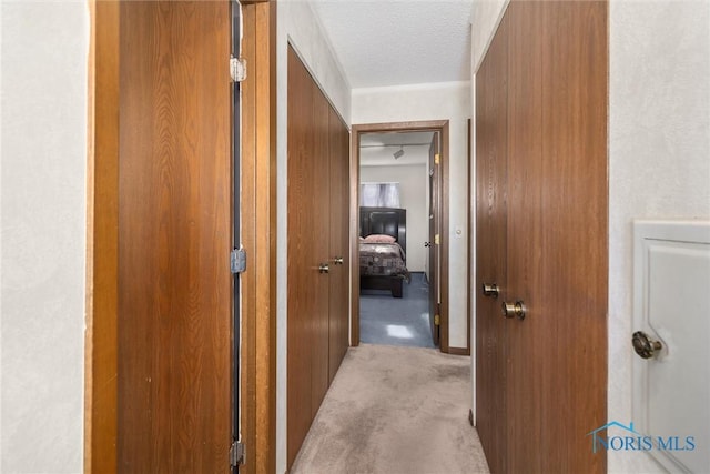 corridor with light colored carpet and a textured ceiling