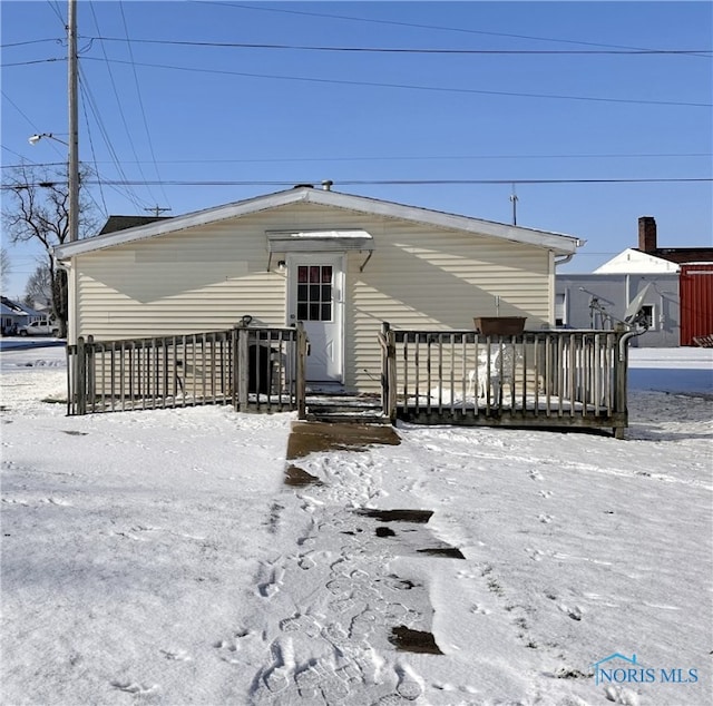 snow covered rear of property with a wooden deck