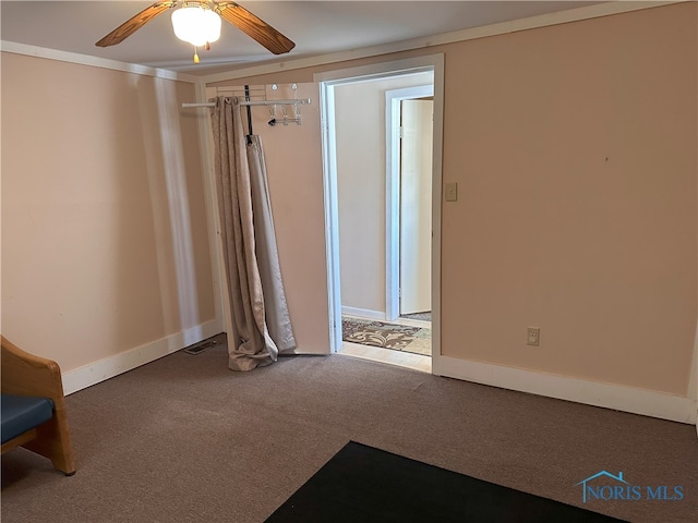 empty room featuring ceiling fan, carpet, and ornamental molding