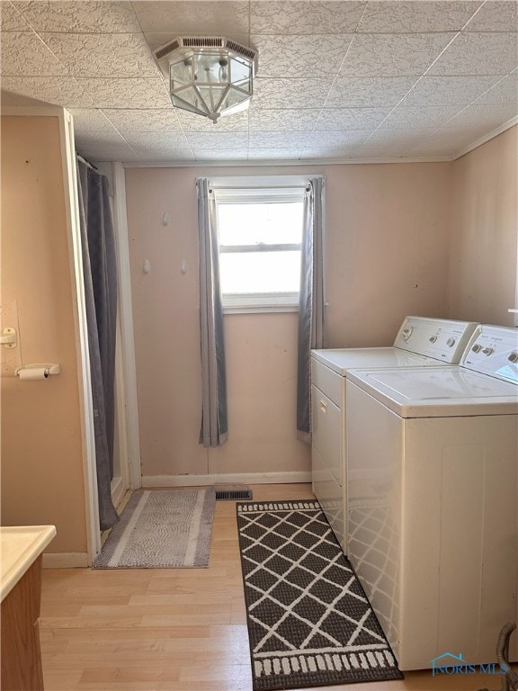 clothes washing area featuring independent washer and dryer and light hardwood / wood-style flooring