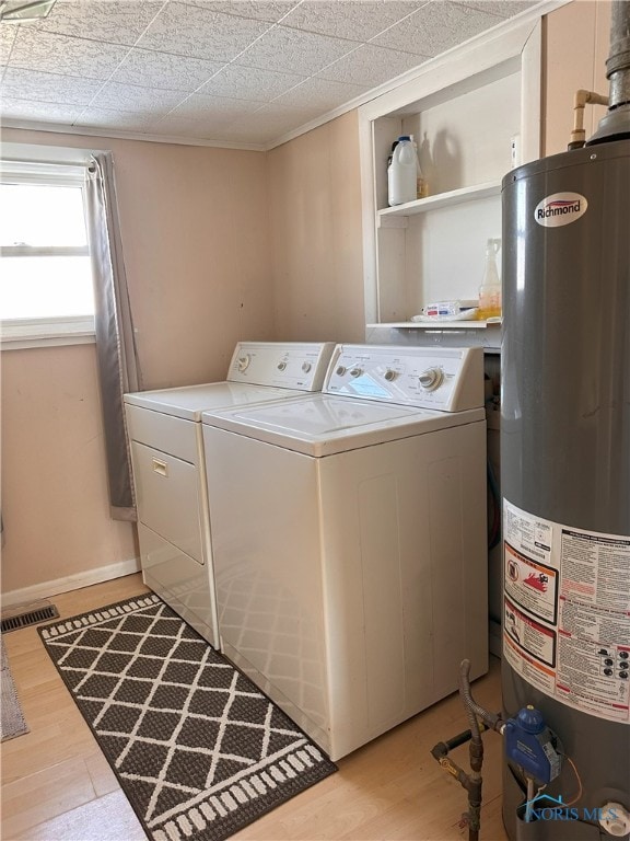 clothes washing area featuring washer and dryer, light wood-type flooring, and gas water heater