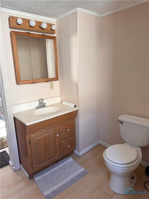 bathroom with ornamental molding, vanity, hardwood / wood-style floors, toilet, and wood walls