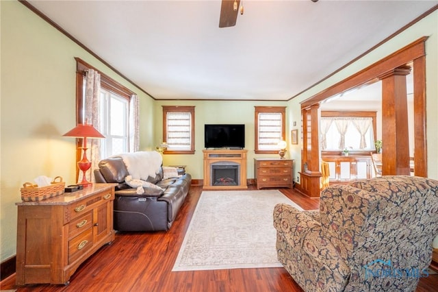 living room with ceiling fan, dark hardwood / wood-style flooring, ornate columns, and ornamental molding