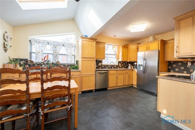 kitchen with backsplash, vaulted ceiling with skylight, pendant lighting, appliances with stainless steel finishes, and light brown cabinetry