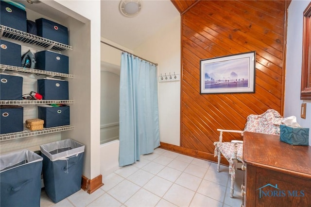 bathroom with tile patterned floors, shower / bath combo, and wooden walls