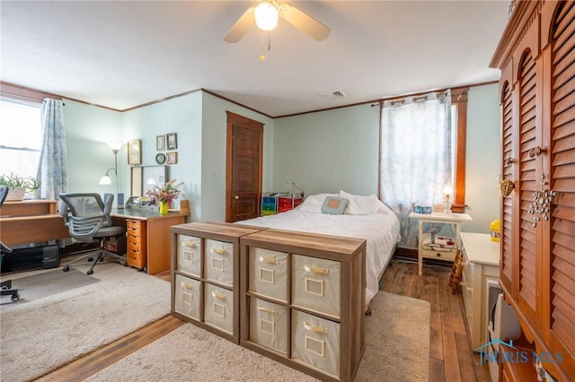 bedroom with ceiling fan, dark hardwood / wood-style floors, crown molding, and multiple windows