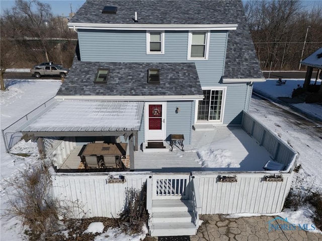 snow covered back of property with a wooden deck