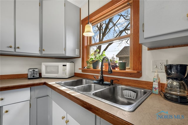 kitchen featuring sink, white cabinets, and pendant lighting