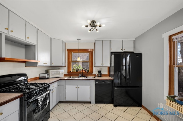 kitchen featuring hanging light fixtures, light tile patterned floors, black appliances, and sink