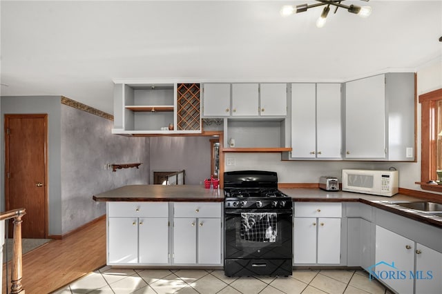 kitchen with gas stove, sink, white cabinets, and light tile patterned flooring