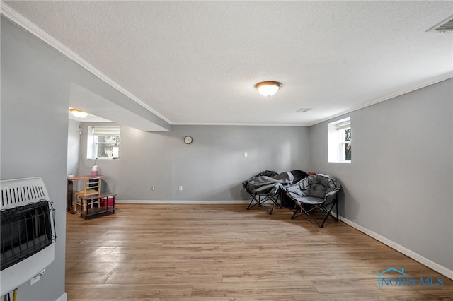 sitting room with ornamental molding, heating unit, and light hardwood / wood-style floors