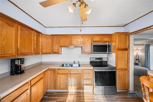 kitchen with ceiling fan, sink, light hardwood / wood-style flooring, ornamental molding, and stainless steel appliances