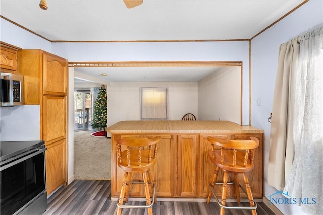 kitchen with kitchen peninsula, dark hardwood / wood-style flooring, stainless steel appliances, and a breakfast bar area