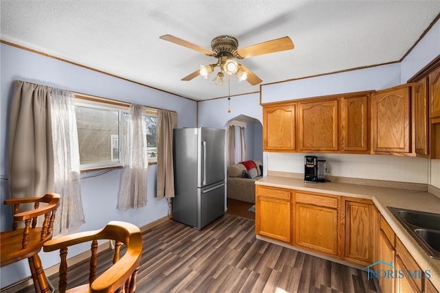 kitchen featuring a textured ceiling, dark wood-type flooring, sink, stainless steel fridge, and ceiling fan