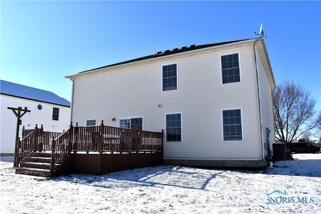 snow covered back of property with a wooden deck