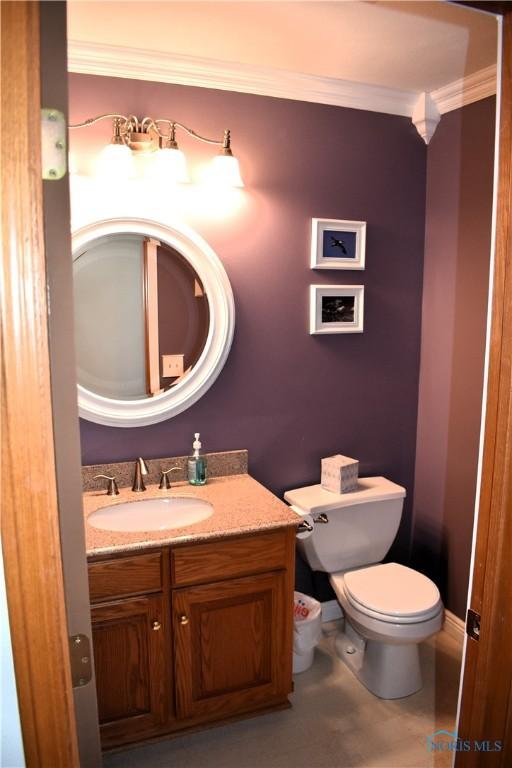 bathroom with tile patterned flooring, vanity, ornamental molding, and toilet