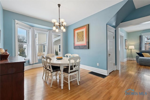 dining room with light wood-type flooring and a notable chandelier