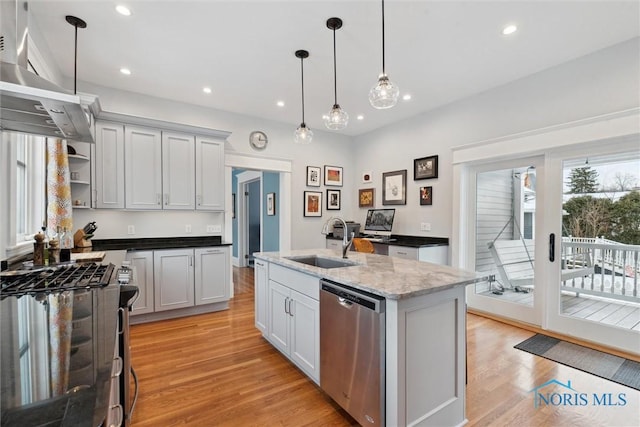 kitchen featuring sink, an island with sink, dark stone counters, decorative light fixtures, and appliances with stainless steel finishes