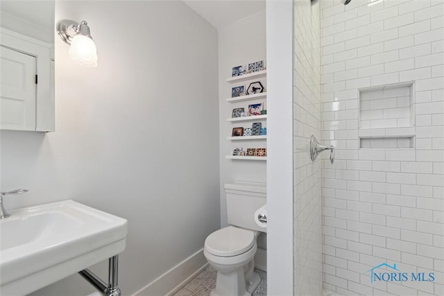 bathroom with sink, toilet, and tiled shower