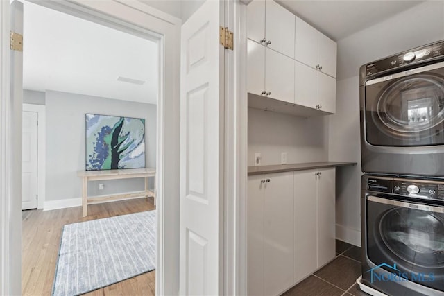 washroom with dark hardwood / wood-style floors, cabinets, and stacked washer / dryer