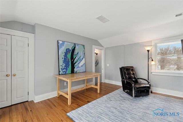 sitting room with light wood-type flooring and vaulted ceiling