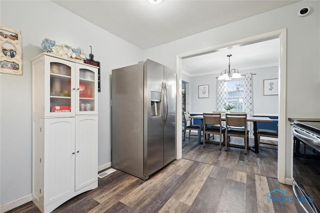 kitchen featuring ornamental molding, stainless steel appliances, dark wood-type flooring, pendant lighting, and a chandelier