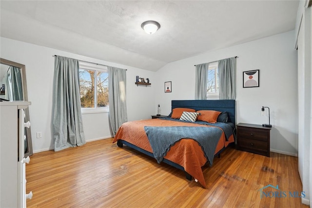 bedroom featuring wood-type flooring, vaulted ceiling, and multiple windows