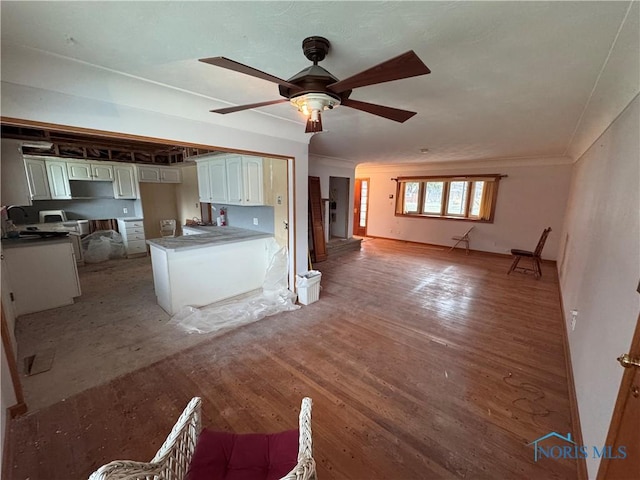 kitchen featuring ceiling fan, sink, kitchen peninsula, white cabinets, and hardwood / wood-style flooring